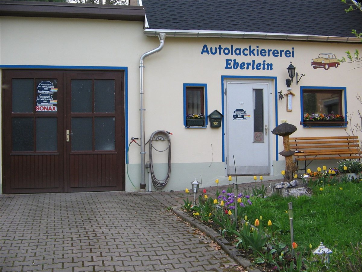 Firmengebäude der Autolackiererei Eberlein in Niedersaida mit Firmenschriftzug, Werkstatttor und Eingang